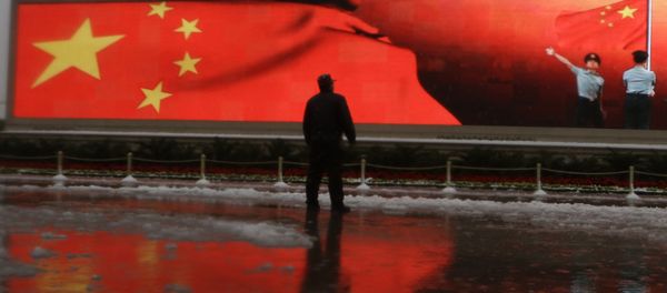 Chinese man stands near a screen displaying the Chinese national flag (File) - Sputnik International