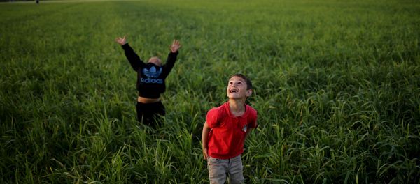 Children look to the sky as they play with a kite in a field at a makeshift camp for migrants and refugees at the Greek-Macedonian border near the village of Idomeni, Greece, April 17, 2016. Children look to the sky as they play with a kite in a field at a makeshift camp for migrants and refugees at the Greek-Macedonian border near the village of Idomeni, Greece, April 17, 2016. - Sputnik International