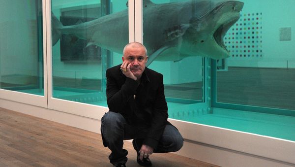 British artist Damien Hirst poses for photographers next to his 1991 work 'The Physical Impossibility of Death in the Mind of Someone Living' during the opening of his solo exhibition showcasing work spanning over two decades at the Tate Modern in central London on April 2, 2012. - Sputnik International