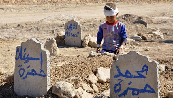 Ali Hamza, 8, sits at the graves of his brother, Mohammed, and sister Asinat, who were killed in a suicide car bomb attack in the Shiite Turkmen village of Qabak near Tal Afar. file photo Ali Hamza, 8, sits at the graves of his brother, Mohammed, and sister Asinat, who were killed in a suicide car bomb attack in the Shiite Turkmen village of Qabak near Tal Afar. file photo - Sputnik International