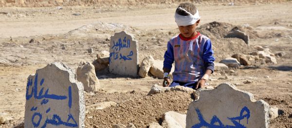 Ali Hamza, 8, sits at the graves of his brother, Mohammed, and sister Asinat, who were killed in a suicide car bomb attack in the Shiite Turkmen village of Qabak near Tal Afar. file photo Ali Hamza, 8, sits at the graves of his brother, Mohammed, and sister Asinat, who were killed in a suicide car bomb attack in the Shiite Turkmen village of Qabak near Tal Afar. file photo - Sputnik International
