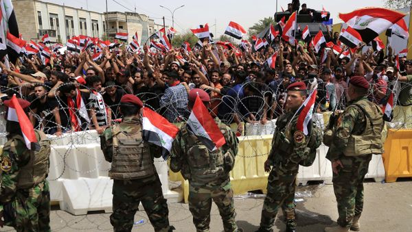 Iraqi security forces guard the heavily fortified Green Zone as followers of Iraq's influential Shiite cleric Muqtada al-Sadr wave national flags as they gather in front of the Green Zone, ahead of a scheduled parliament session to press for a vote on a new government, in Baghdad, Iraq, Tuesday, April 26, 2016. - Sputnik International