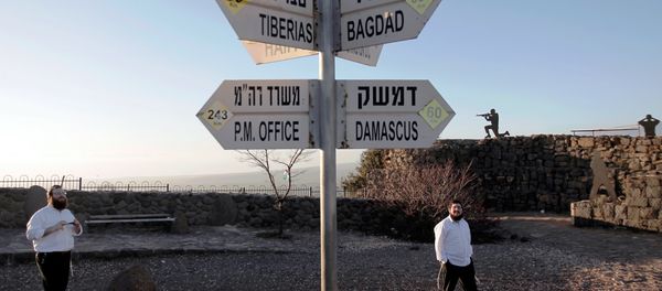 Israelis walk near a sign for tourists showing the distance to Damascus and Baghdad among other destinations at an army post on Mount Bental in the Israeli-annexed Golan Heights on March 10, 2016. Israelis walk near a sign for tourists showing the distance to Damascus and Baghdad among other destinations at an army post on Mount Bental in the Israeli-annexed Golan Heights on March 10, 2016. - Sputnik International