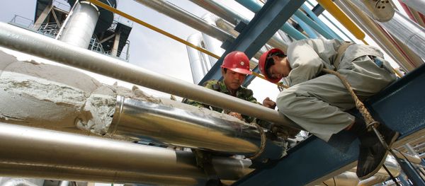 Workers repair pipes at the Yanlian Oil Refinery in Yan'an, 25 May 2005, north of Xian in western China's Shaanxi province - Sputnik International