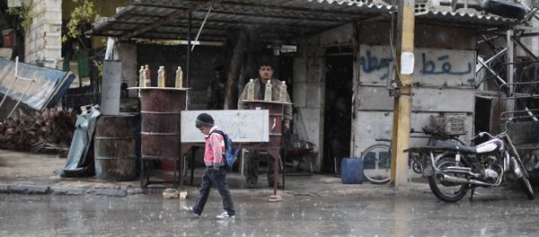 A Syrian schoolboy walks under the rain in Kafr Batna, in the Eastern Ghouta area, on the outskirts of the capital Damascus (File) - Sputnik International