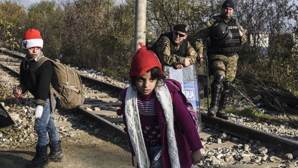 Police officers watch two children walk past as migrants and refugees cross the Greek-Macedonian border near the town of Gevgelija, Macedonia (File) Police officers watch two children walk past as migrants and refugees cross the Greek-Macedonian border near the town of Gevgelija, Macedonia (File) - Sputnik International