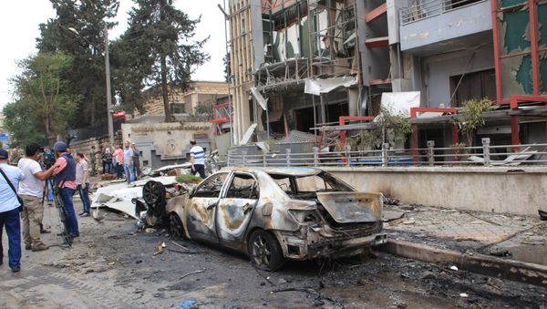 Journalists and civilians stand near the damage after rockets fired by insurgents hit the al-Dabit maternity clinic in government-held parts of Aleppo city, Syria, in this handout picture provided by SANA on May 3, 2016 - Sputnik International