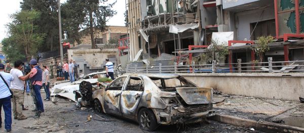 Journalists and civilians stand near the damage after rockets fired by insurgents hit the al-Dabit maternity clinic in government-held parts of Aleppo city, Syria, in this handout picture provided by SANA on May 3, 2016 - Sputnik International