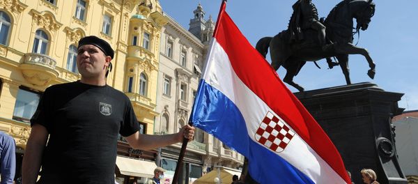 A man holds the Croatian flag as he takes part to a march in support of the Homeland War veterans' rights in Zagreb on April 14, 2015. Croatian leaders April 22, 2016, honoured the victims of the Balkan country's most notorious World War II death camp, in an event boycotted by critics who accuse rulers of tolerating a revival of pro-Nazi ideology - Sputnik International