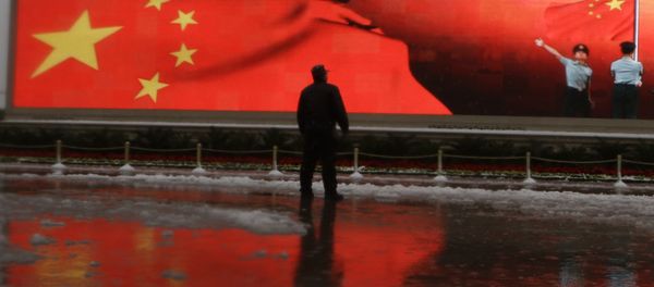 Chinese man stands near a screen displaying the Chinese national flag Chinese man stands near a screen displaying the Chinese national flag - Sputnik International