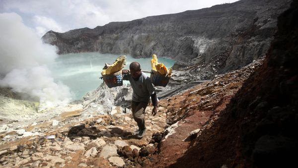 In this April 16, 2016 photo, Marzuki, a sulfur miner, carries baskets of sulfur as he climbs up from the crater of Mount Ijen in Banyuwangi, East Java, Indonesia - Sputnik International