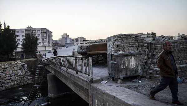 People walk past a burned truck at the entrance of Nusaybin on December 24, 2015, in Mardin - Sputnik International
