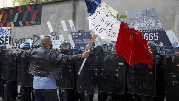 A man holds a French flag with the message, No to the El Khomri law in front of a line of French riot police during a protest against the French labour law proposal during the May Day labour union march in Paris, France, May 1, 2016. A man holds a French flag with the message, No to the El Khomri law in front of a line of French riot police during a protest against the French labour law proposal during the May Day labour union march in Paris, France, May 1, 2016. - Sputnik International