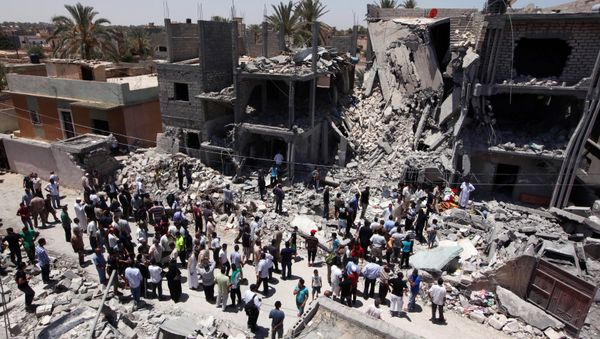 Libyans gather next to the rubble of buildings the Libyan authorities said were damaged by airstrikes on Tripoli's residential district of Arada (File) Libyans gather next to the rubble of buildings the Libyan authorities said were damaged by airstrikes on Tripoli's residential district of Arada (File) - Sputnik International