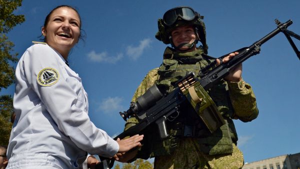 A visitor stands next to a marine demonstrating a Pecheneg machine gun during an exhibition of armaments and special equipment held as part of the Innovation Day at the Eastern Military District in Vladivostok - Sputnik International