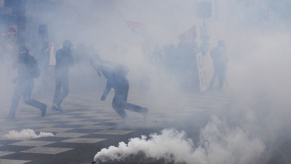 Protesters run from tear gas canisters during clashes with police at a demonstration after the French government used the constitution's Article 49,3 to bypass parliament and force through a controversial labour reform bill, on May 17, 2016, in Paris - Sputnik International