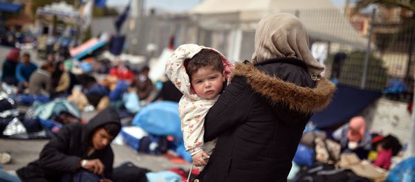 A Syrian woman holds her child at the port of Chios on April 3, 2016 as refugees and migrants who broke out from Chios detention camp, stand in the port of the city. - Sputnik International
