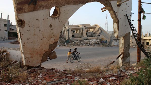A picture taken through an arch remaining from a detroyed building shows Syrian boys on a bicycle on May 14, 2016 in the southern Syrian city of Daraa.  - Sputnik International