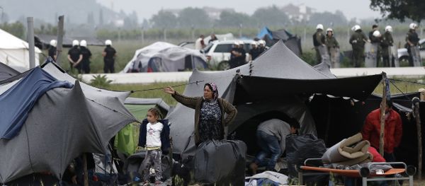 A migrant family stands outside their tent during an evacuation operation by police forces of a makeshift migrant camp at the border at the Greek-Macedonian border near the village of Idomeni, on May 24, 2016 - Sputnik International