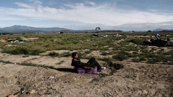 Syrian Kurd Nidal Daud, 37, sits on a suitcase as he waits to be transferred to a hospitality centre during a police operation at a refugee camp at the border between Greece and Macedonia, near the village of Idomeni, Greece, May 25, 2016 - Sputnik International