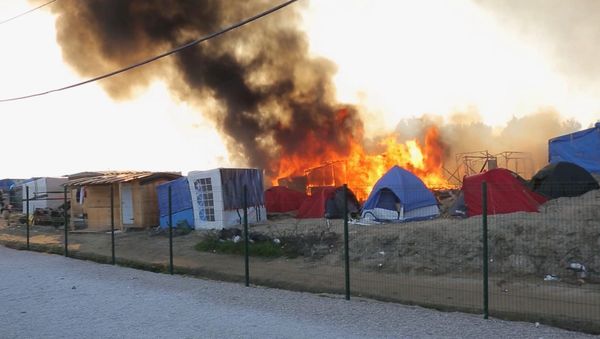 Smoke rises from the huts and tents set on fire during clashes between migrants, at a makeshift camp, in Calais, France, Thursday, May 26, 2016 - Sputnik International
