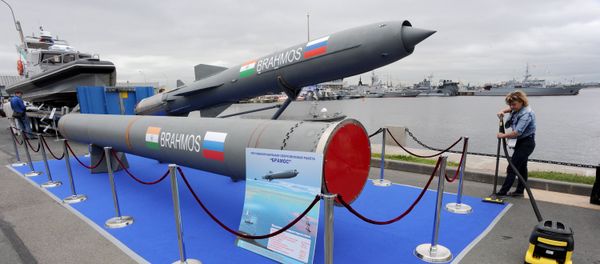 A woman cleans a carpet flooring close to a Brahmos supersonic cruise missile at the International Maritime Defence Show in St. Petersburg on July 2, 2015. - Sputnik International