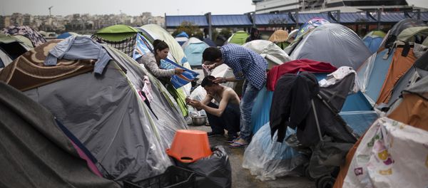 A man cuts another man's hair outside a passenger terminal used as a shelter for refugees and migrants at the Piraeus harbour in Athens on April 3, 2016 - Sputnik International