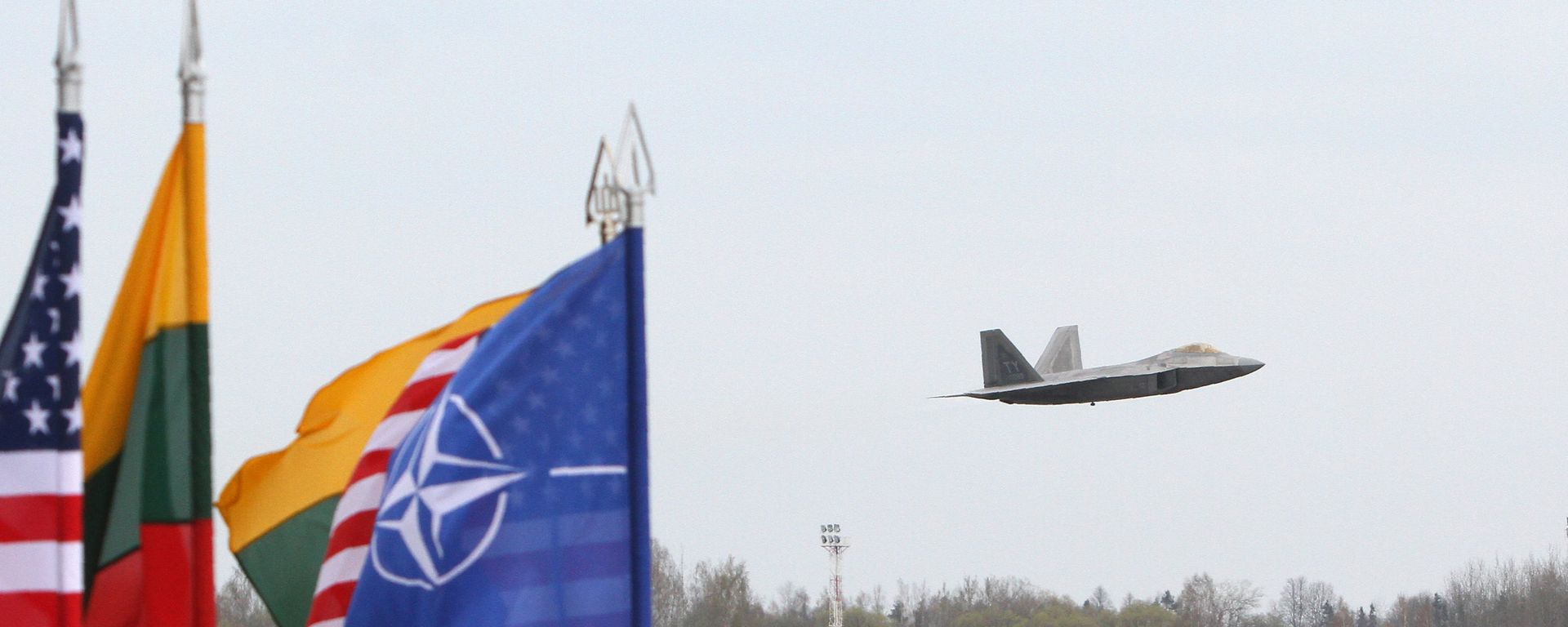 A US Air Force F-22 Raptor fighter aircraft flies at the Air Base of the Lithuanian Armed Forces in Šiauliai, Lithuania, on April 27, 2016 behind flags of US, Lithiania and the NATO - Sputnik International, 1920, 13.07.2022