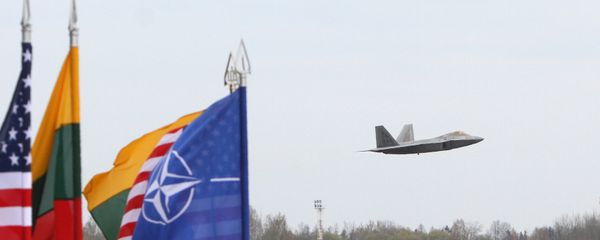 A US Air Force F-22 Raptor fighter aircraft flies at the Air Base of the Lithuanian Armed Forces in Šiauliai, Lithuania, on April 27, 2016 behind flags of US, Lithiania and the NATO - Sputnik International