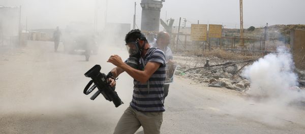Palestinian journalists run for cover from tear gas canisters fired by Israeli forces during a demonstration in support of Palestinian journalists on the occasion of the World Press Freedom day outside the compound of the Israeli-run Ofer prison near Betunia in the occupied West Bank, on May 3, 2016 Palestinian journalists run for cover from tear gas canisters fired by Israeli forces during a demonstration in support of Palestinian journalists on the occasion of the World Press Freedom day outside the compound of the Israeli-run Ofer prison near Betunia in the occupied West Bank, on May 3, 2016 - Sputnik International