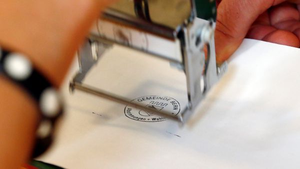 A ballot paper gets a stamp in a ballot office during a vote on whether to give every adult citizen a basic guaranteed monthly income of 2,500 Swiss francs ($2,560), in a school in Bern, Switzerland, June 5, 2016. - Sputnik International