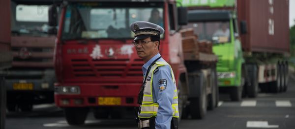 Policeman gestures in front of trucks, China Policeman gestures in front of trucks, China - Sputnik International