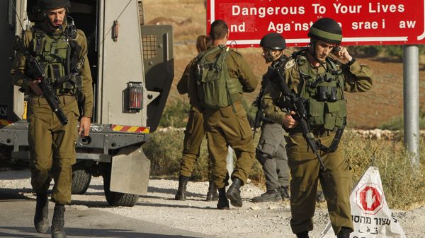 Israeli soldiers are seen at one of the entrances of the Palestinian village of Yatta in the occupied West Bank on June 9,2016 after the army entered the village in search for clues leading to an attack the previous night in the Israeli city of Tel Aviv in which four people were killed and 16 others wounded - Sputnik International
