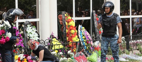 A woman places flowers as Interior Ministry members stand guard outside the firearms shop, which was a target of a recent suspected Islamist militant attack, during the funeral of salesman Andrey Maksimenko in Aktobe, Kazakhstan, June 8, 2016 - Sputnik International