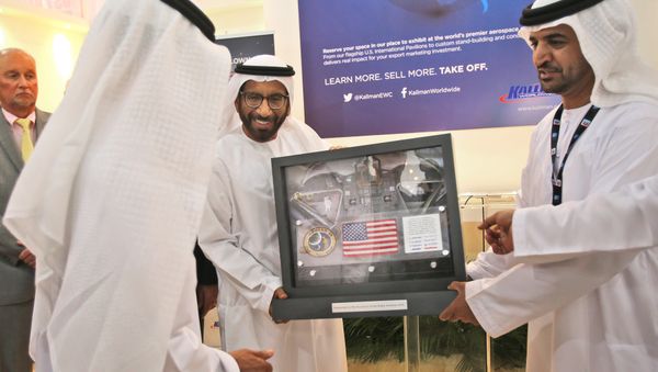Khalifa Mohammed Al Rumaithi, Chairman of the UAE Space Agency, center, receives a United States of America flag and other memorabilia from the 1971 Apollo 14 lunar mission from Kallman Worldwide during the third day of the Dubai Airshow in the United Arab Emirates, Tuesday, Nov. 10, 2015. - Sputnik International