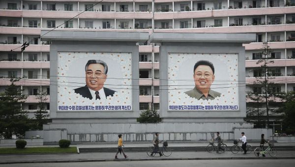North Koreans are dwarfed against giant portraits of the late North Korean leaders Kim Il Sung and Kim Jong Il as they walk past an apartment building on Wednesday, June 22, 2016, in Wonsan, North Korea. - Sputnik International