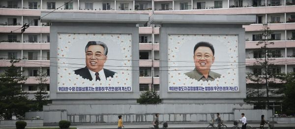 North Koreans are dwarfed against giant portraits of the late North Korean leaders Kim Il Sung and Kim Jong Il as they walk past an apartment building on Wednesday, June 22, 2016, in Wonsan, North Korea. - Sputnik International