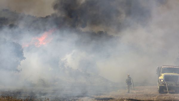 A firefighter is dwarfed by a burning mountain at the 6,500 acre Border Fire in eastern San Diego County, California, in the late afternoon on June 22, 2016. - Sputnik International