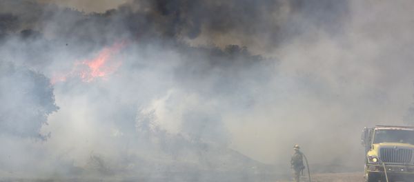 A firefighter is dwarfed by a burning mountain at the 6,500 acre Border Fire in eastern San Diego County, California, in the late afternoon on June 22, 2016. - Sputnik International