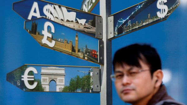 A man walks past various currency signs, including the dollar (top R), Australian dollar (top L), pound sterling (centre L) and Euro (bottom L), outside a brokerage in Tokyo October 28, 2014 - Sputnik International