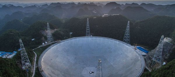 In this photo released by China's Xinhua News Agency, the sun sets above the Five-hundred-meter Aperture Spherical Telescope (FAST) in Pingtang County in southwestern China's Guizhou Province Monday, June 27, 2016 - Sputnik International