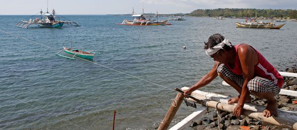 A fisherman repairs his boat overlooking fishing boats that fish in the disputed Scarborough Shoal in the South China Sea, at Masinloc, Zambales, in the Philippines (File) - Sputnik International