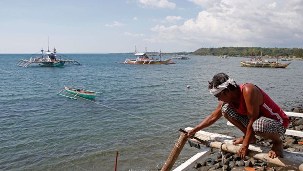 A fisherman repairs his boat overlooking fishing boats that fish in the disputed Scarborough Shoal in the South China Sea, at Masinloc, Zambales, in the Philippines (File) A fisherman repairs his boat overlooking fishing boats that fish in the disputed Scarborough Shoal in the South China Sea, at Masinloc, Zambales, in the Philippines (File) - Sputnik International