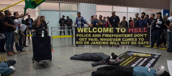Police officers and firemen welcome passengers with a banner reading Welcome to Hell as they protest against the government for delay in their salary payments at Tom Jobim International Airport in Rio de Janeiro, Brazil, July 4, 2016 - Sputnik International