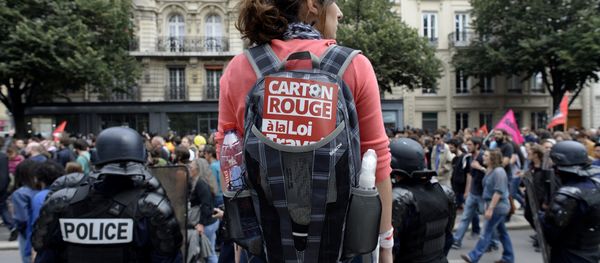 A woman carrying a backpack with a sticker reading Red card to the labour law stands behind French CRS anti-riot police during a demonstration against the government's proposed labour reforms in Paris on July 5, 2016 A woman carrying a backpack with a sticker reading Red card to the labour law stands behind French CRS anti-riot police during a demonstration against the government's proposed labour reforms in Paris on July 5, 2016 - Sputnik International