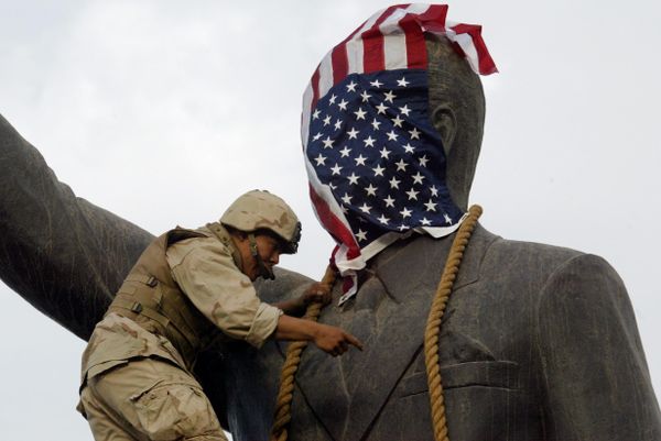 A US Marine covers the head of a statue of Iraqi President Saddam Hussein with the US flag before pulling it down in Baghdad's al-Fardous (paradise) square 09 April 2003 as the marines swept into the Iraqi capital and the Iraqi leader's regime collapsed. - Sputnik International