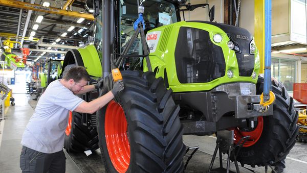 A worker adjusts the front wheel of a tractor on the assembly line of the Claas tractor manufacturer plant (File) A worker adjusts the front wheel of a tractor on the assembly line of the Claas tractor manufacturer plant (File) - Sputnik International