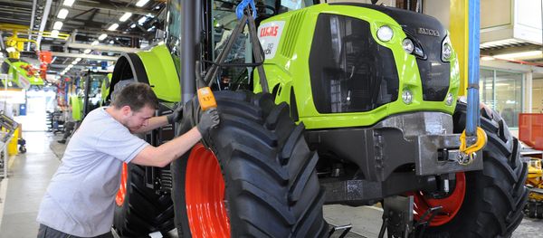 A worker adjusts the front wheel of a tractor on the assembly line of the Claas tractor manufacturer plant (File) A worker adjusts the front wheel of a tractor on the assembly line of the Claas tractor manufacturer plant (File) - Sputnik International