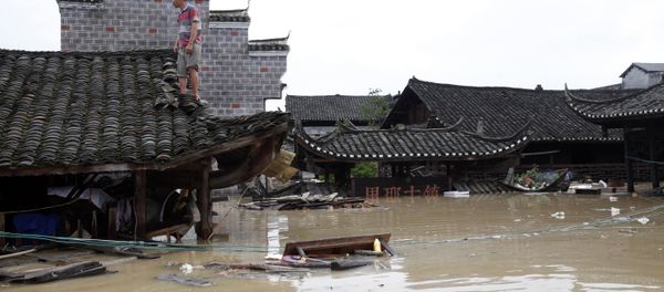 Man standing on the rood of a flood-inundated building in the flooded ancient town of Longshan county, central China's Hunan province - Sputnik International