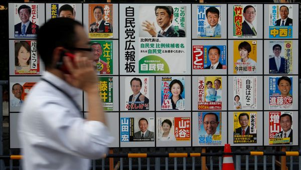 A man walks past Japan's ruling Liberal Democratic Party's (LDP) poster (C) for the July 10 upper house election with the image of Shinzo Abe, Japan's Prime Minister and leader of the LDP, and other candidates' posters at the LDP headquarters in Tokyo, Japan July 10, 2016 - Sputnik International